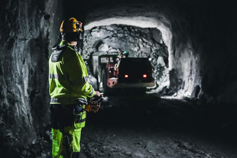 En arbetare styr en maskin i en mörk tunnel i Garpenbergs gruva som lastar och transporterar malm