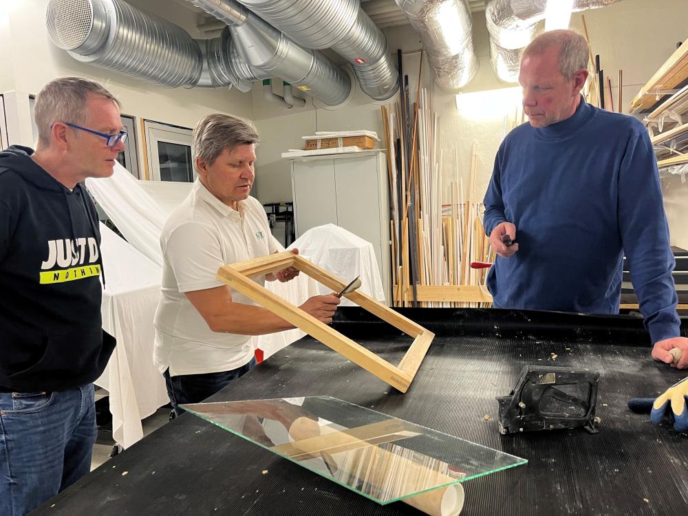 Joakim Länder instruerar två bygglärare i hur man kittar en fönsterbåge 