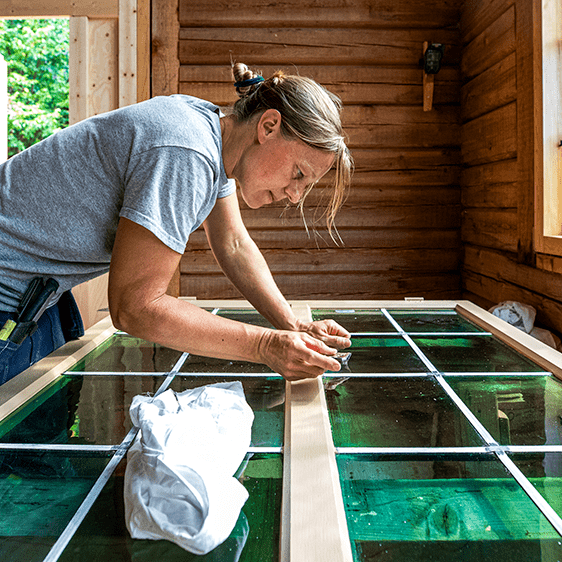 En kvinna renoverar ett fönster med gröna glas