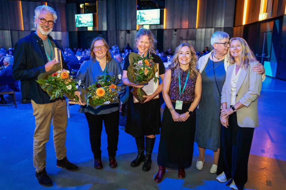 6 personer står uppställda inomhus med blombuketter i handen efter ceremonin under SM i konstinramning.