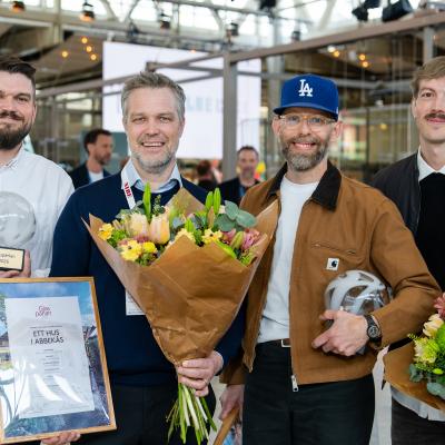 Fyra glada personer med blommor och diplom