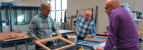 En utbildare instruerar två bygglärare i en glasövning på Glasskolan i Katrineholm