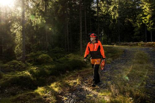 Magnus Höij i skogen, iklädd arbetskläder och bär på en röjsåg