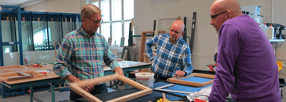 En utbildare instruerar två bygglärare i en glasövning på Glasskolan i Katrineholm