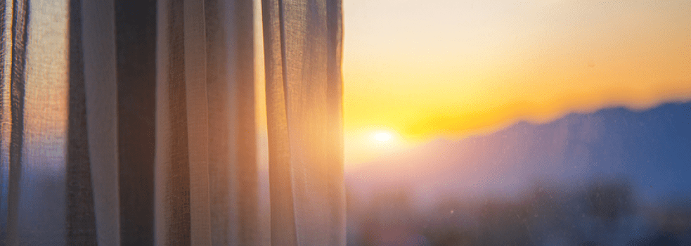 Solnedgång i fjällandskap genom ett fönster