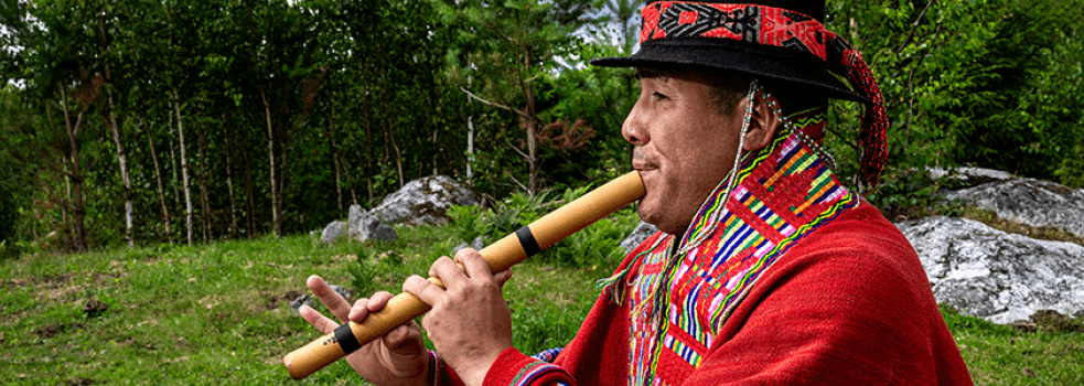 Man spelar flöjt i röd peruanskt folkdräkt