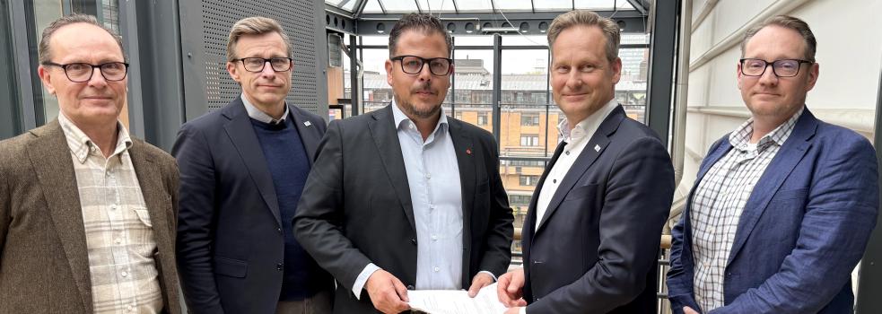 Fem män i kostym, med glasmästeriavtalet i handen.