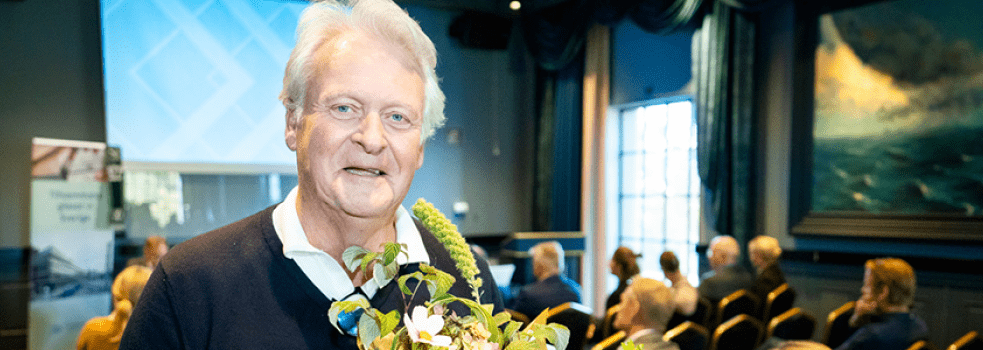 Man med blommor i handen tittar leendes in i kameran