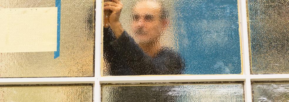 Ett fönster med en man bakom som syns blurrigt