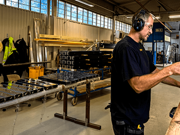 En man arbetar i produktion på ett glas- och metallföretag.