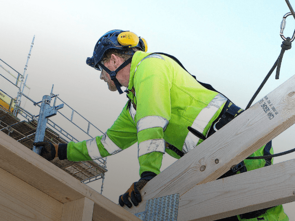 En byggnadsarbetare är säkrad med sele i en lina. 