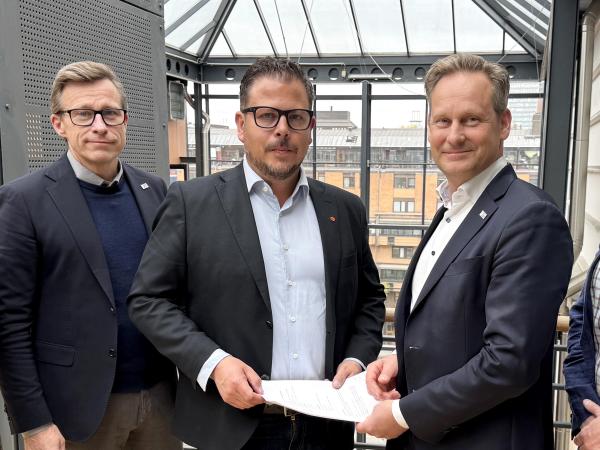 Fem män i kostym, med glasmästeriavtalet i handen.