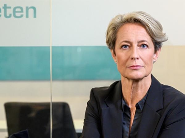 Kvinna i blont hår och kavaj tittar in i kameran