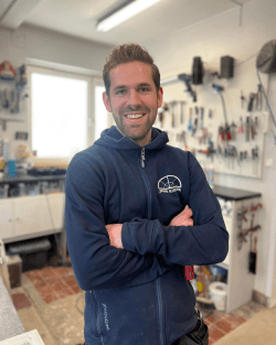 Glasmästare i blå hoodie står med armarna i kors