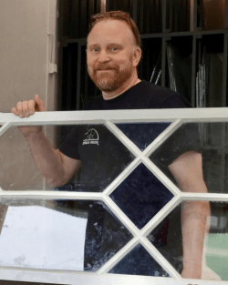 Glasmästare håller i ett renoverat fönster