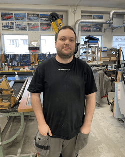 Stefan Hedin, lärling på Borlänge Glasmästeri i svart t-shirt och grå arbetsbyxor